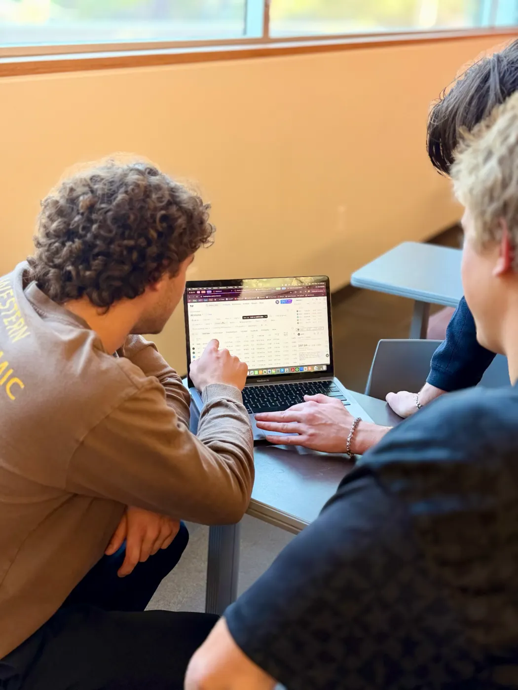 Students collaborating around a laptop